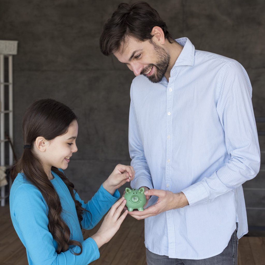 high-angle-father-daughter-with-piggy-bank