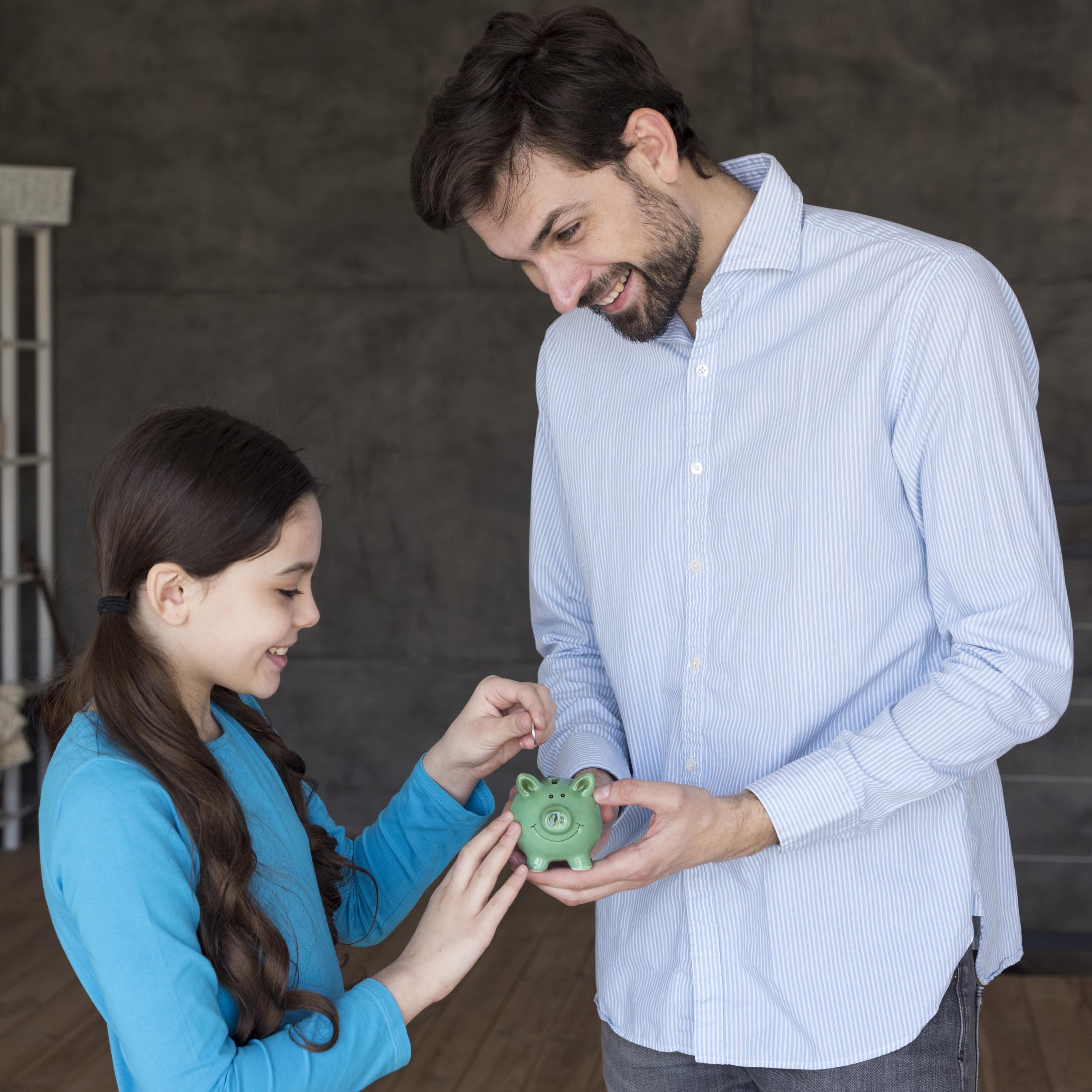 high-angle-father-daughter-with-piggy-bank