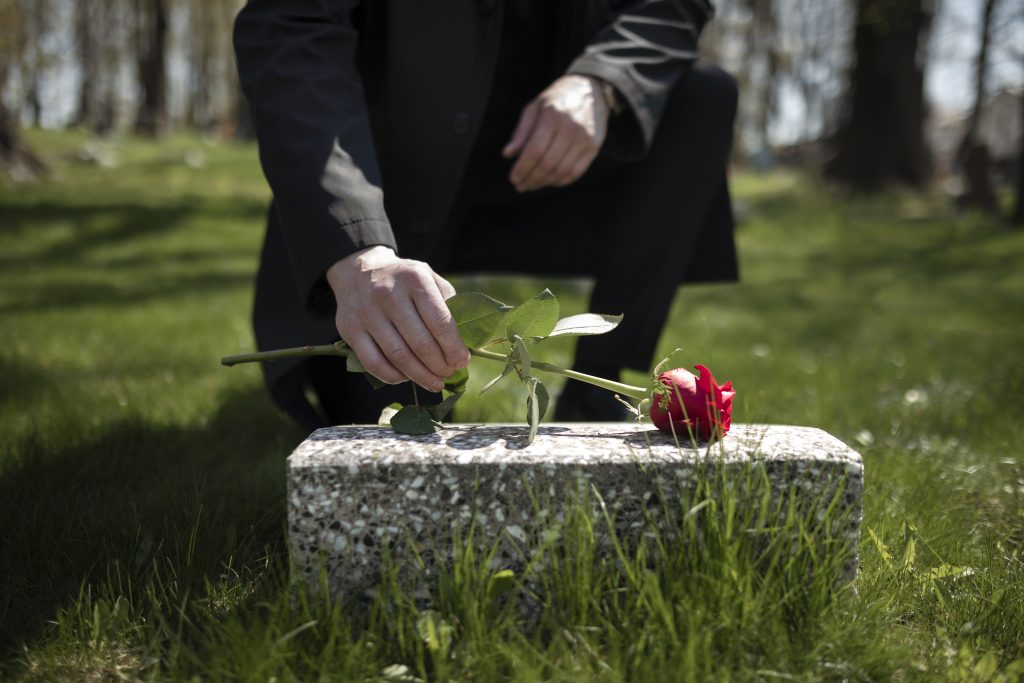 man-bringing-rose-tombstone-cemetery